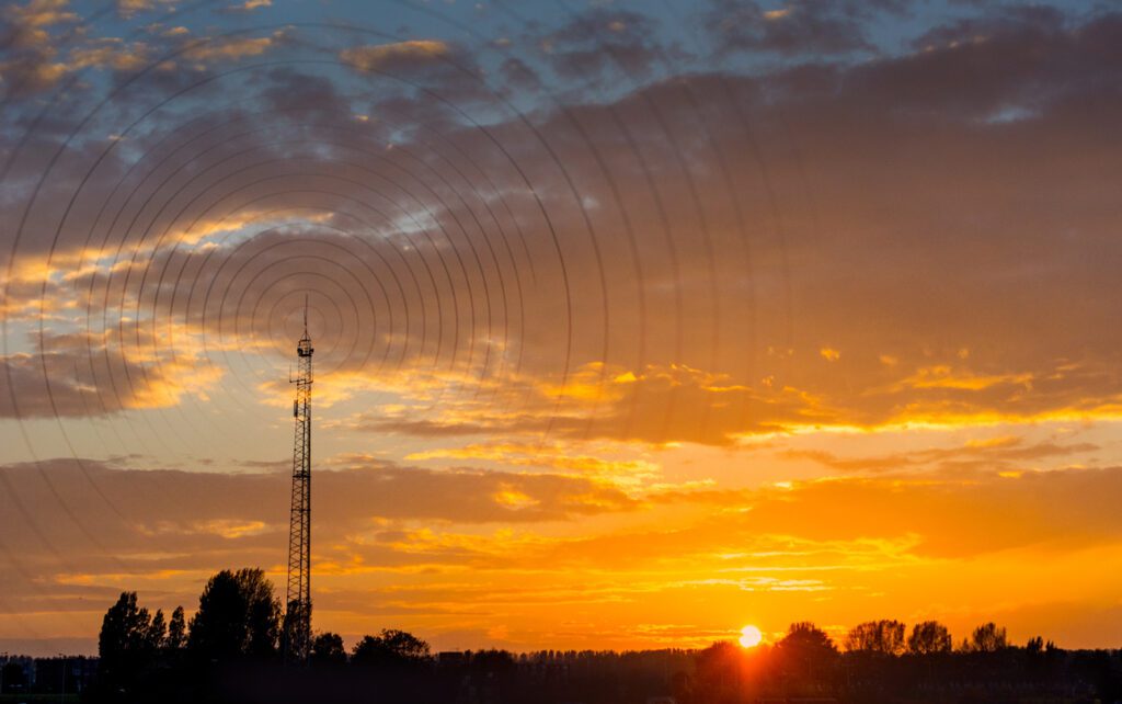 Radio waves escaping from gsm tower visualisation at sunset in rural area to demonstrate Fixed Wireless Internet vs Satellite