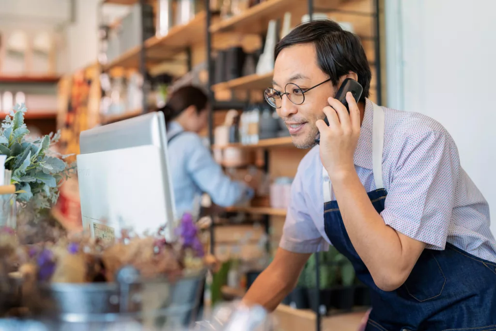 A small business owner in an apron taking a call on his VoIP phone system